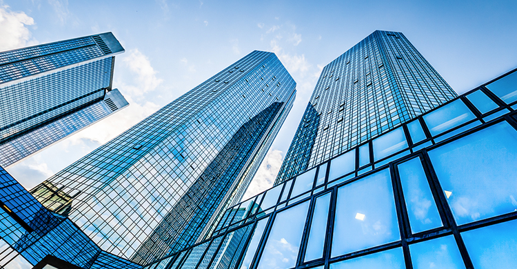 Ground view looking up of several glass skyscrapers against a blue sky